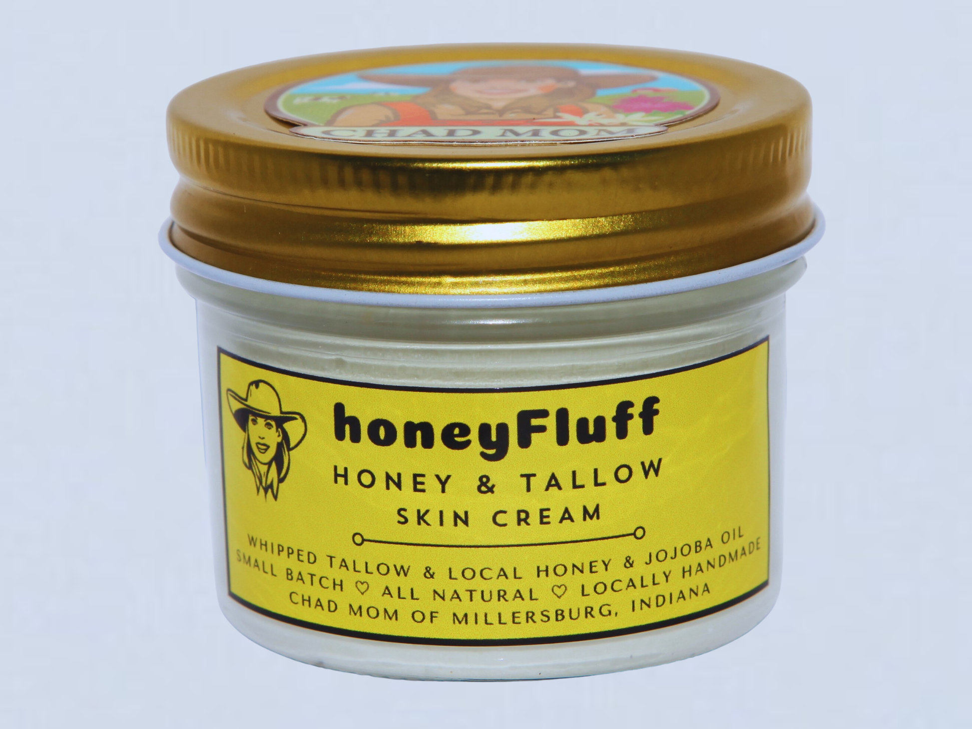 Jar of honeyFluff Honey & Tallow Skin Cream with gold lid on a light blue background
